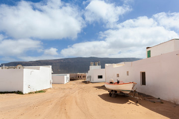 Empty street with sand and white houses in Caleta de Sebo on the island La Graciosa