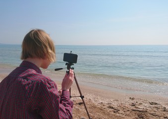 teenager boy takes pictures of the sea