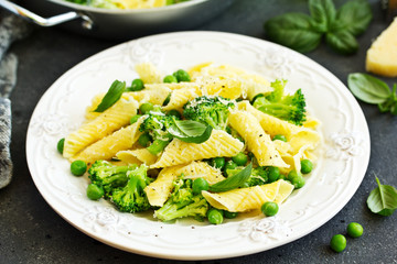 penne pasta with spinach pesto sauce, green peas and broccoli, top view
