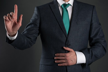 Businessman is showing his index finger up on a gray background. Attention please. Business statement.