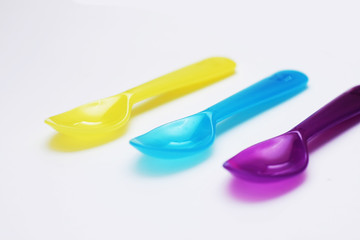 Little empty colorful spoons in white background.
