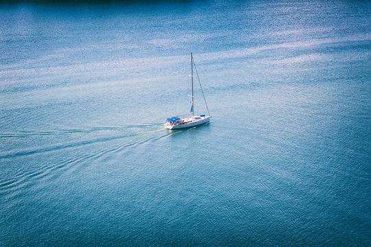 Single sailboat on the blue sea water background, summer travel and vacation concept