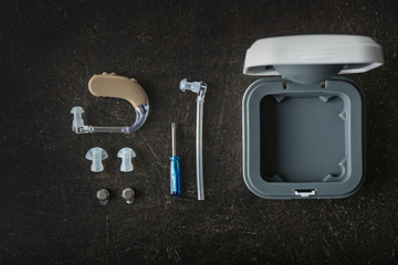 Hearing aid with accessories on dark background