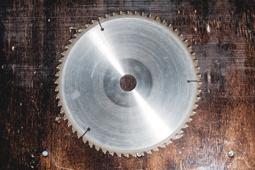 Close-up used blade circular saw on the background of the wooden table. Workshop for the production of wooden products. Joiner's cutting tool