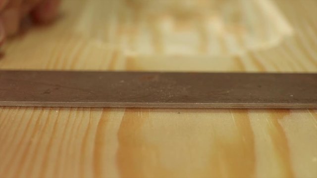 A Macro shot of carpenter using a Pencil and Hardwood square on a peice of Timber