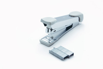 Stapler and staple on plain white background