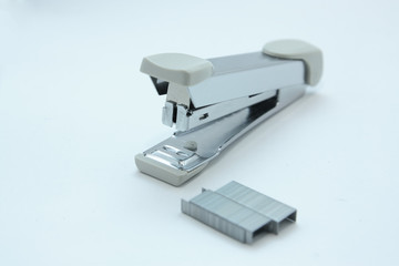 Stapler and staple on plain white background