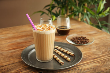 Tray with glass of tasty frappe coffee on wooden table