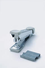 Stapler and staple on plain white background
