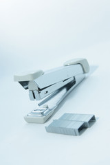 Stapler and staple on plain white background