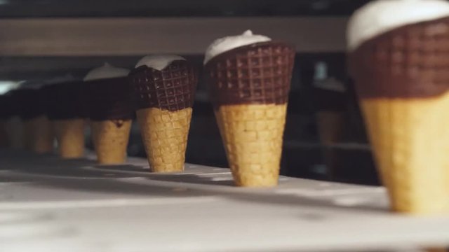 ice cream production, transportation waffle-cone with plombir ice cream on conveyor, production line, dairy products.