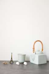 Fototapeta na wymiar White ceramic Asian Japanese teapot with wooden handle and white ceramic teacup on gray table top on white wall background with empty text copy space. Minimalism.