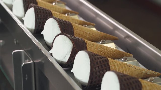 ice cream production, transportation waffle-cone with plombir ice cream on conveyor, production line, dairy products.