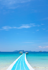 Plastic floating walkway bridge and pier on blue sea water in tropical island under bright blue sky in sunny day 