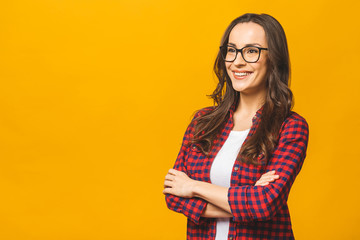 Portrait of a pretty smiling woman in casual and glasses posing isolated on a yellow background.