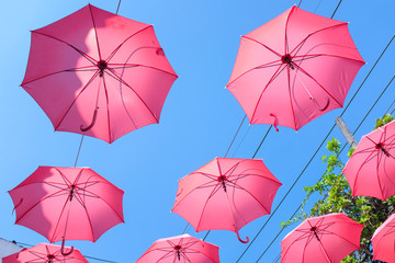 Bright red umbrellas hanging in the air with clear blue sky background