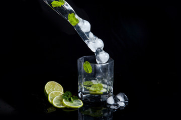 Summer cocktail mojito with splash on black background..
