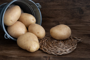 Close-up of potatoes in metal bucket on dark wood background