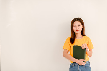 Asian girl holding a green book in front of her