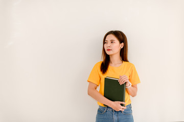 The girl holds a green book with vivid life photographs on a lonely white background.