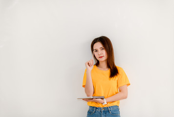 The girl standing holding writing in a notepad while standing on a white background