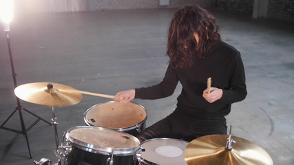A man with long hair playing drums and sets the rhythm