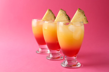 Glasses of Tequila Sunrise cocktail on color background