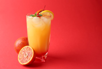 Glass of Tequila Sunrise cocktail on color background