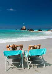 Couple on sunbeds relaxing at the beach in Lefkada