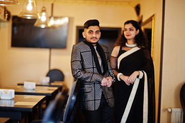 Lovely indian couple in love, wear at saree and elegant suit, posed on restaurant.