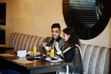 Lovely indian couple in love, wear at saree and elegant suit, posed on restaurant.