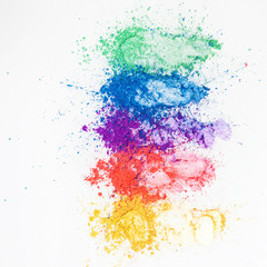 Bright eye shadows in different colors of the rainbow, scattered on a white background.