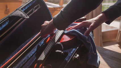 Person cleaning violin inside the case