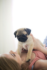 Pug puppy at hostess in her arms, Caucasian woman