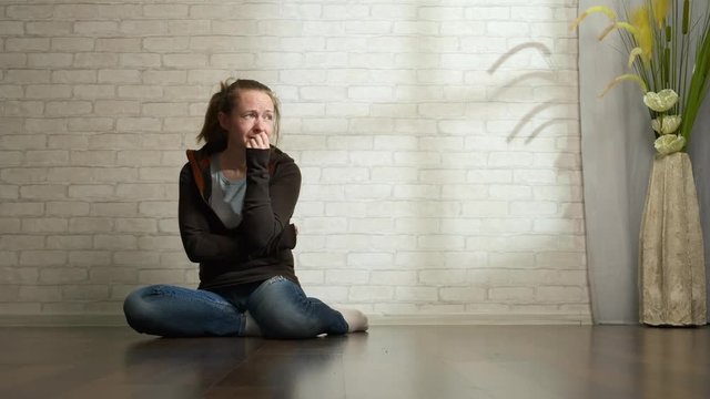 Depressed man is crying while sitting on the floor near the wall at home alone.
