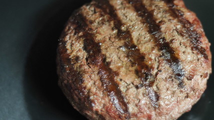 The finished meat patty with a grill imprint is smeared with vegetable olea