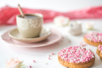 rusk with pink and white aniseed, Dutch Muisjes. Traditional treat when a baby girl is born in The Netherlands. Cup of tea on white table.