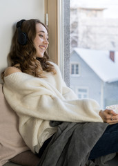 Girl sitting near the window, hold big white mag cacao with marshmallow. Home cozy lifestile photo