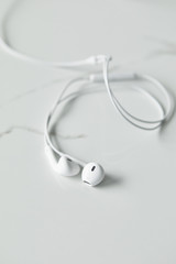 selective focus of white earphones on white surface with copy space