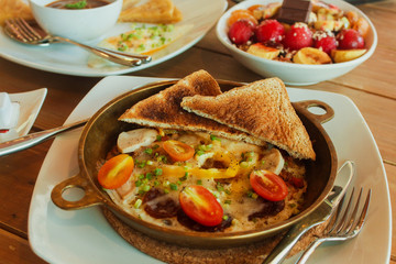 Breakfast table with omelet sandwich, fresh fruit