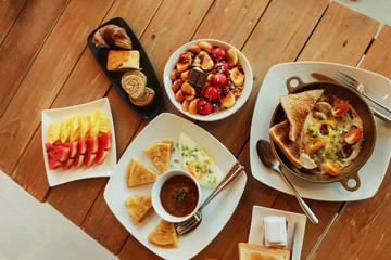 Breakfast table with omelet sandwich, fresh fruit, cookies and Shahi Paneer. top view