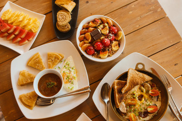 Breakfast table with omelet sandwich, fresh fruit, cookies and Shahi Paneer. top view