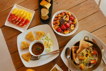 Breakfast table with omelet sandwich, fresh fruit, cookies and Shahi Paneer. top view