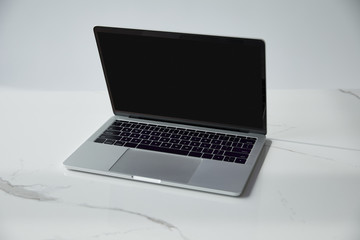 laptop with blank screen and black keyboard on white marble surface isolated on grey
