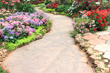Walkway in garden with nature colorful ornamental flowers background