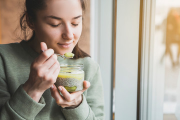 Pretty happy young pretty mixed race female eating dessert in a jar while looking away. Horizontal Shot