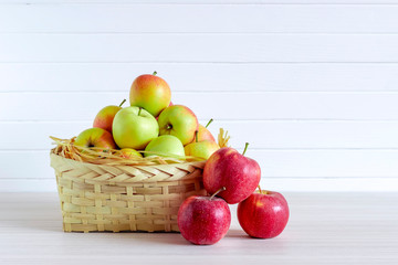 Basket with apples on wooden white table, insulation on white background.
