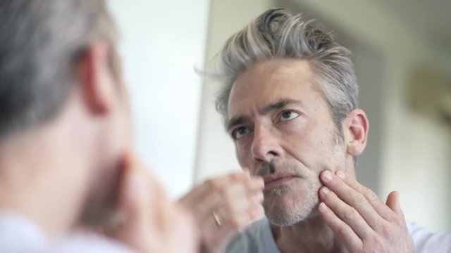 Mature man looking at himself in mirror