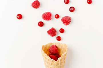 Ice cream cone filled with .raspberry and cranberries on a white background. Frosen berries .fall out from a waffle cone. Summer concept.
