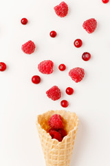 Ice cream cone filled with .raspberry and cranberries on a white background. Frosen berries .fall out from a waffle cone. Summer concept.